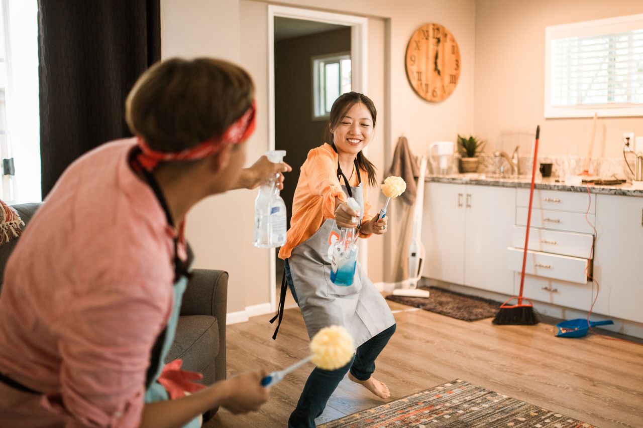 A couple from Asia enjoying themselves while tidying their home, creating a bright and cheerful mood.